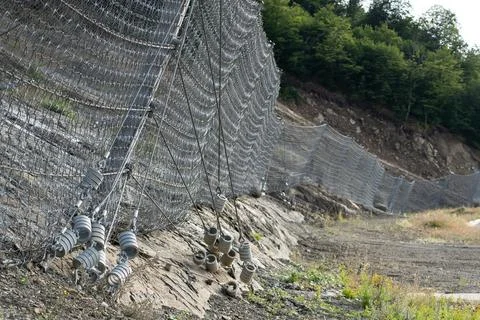 Active robust rockfall barrier system with wire mesh along the road, brake for Stock Photos