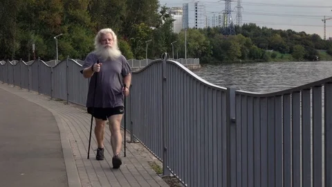 Active senior Caucasian man training Nordic walking with trekking poles Vídeos de archivo 121028345