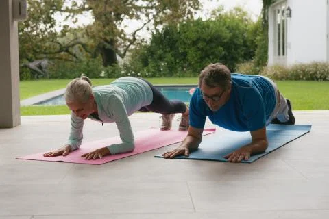 Active senior couple doing plank exercise in the porch at home Fotos Stock