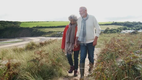Active Senior Couple Holding Hands As They Walk Along Coastal Path In Fall Stock Footage 124573033
