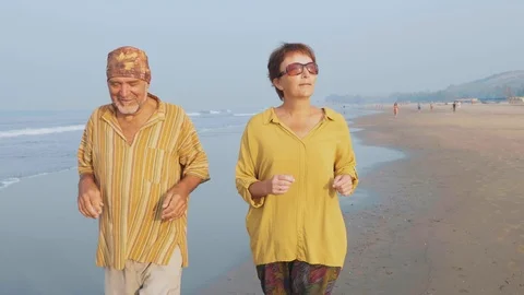 Active senior couple running on the sandy beach at sunrise Video stock 101274710