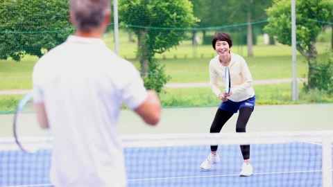 Active Senior Japanese Couple Playing Tennis Together on Outdoor Court Vídeos de archivo 344013554