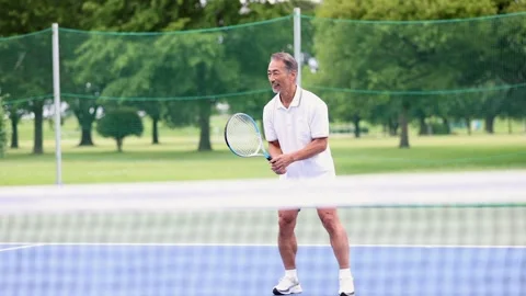 Active Senior Japanese Man Playing Tennis on Outdoor Court Stock Footage 344009816
