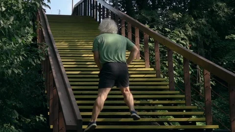 Active senior man doing exercises on wood stairs and running up. Rear view. 動画素材 116055972