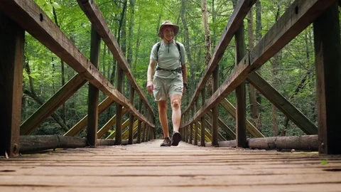Active Senior Man Hiking Across a Bridge - 4k Stock Footage 117128059
