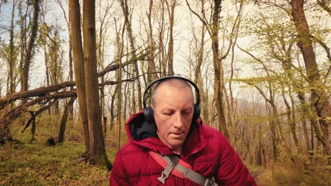 Active senior man hiking in spring forest wearing headphones, mature healthy Video stock 333186315