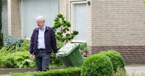 Active senior man puts garbage can along street Stock Footage 57263159