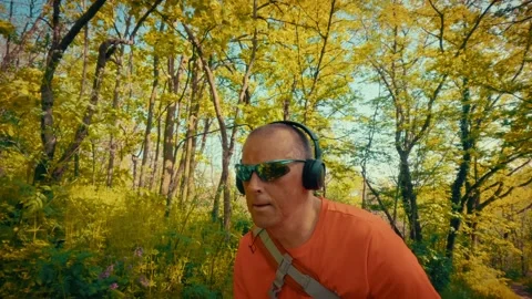 Active senior using tech in nature, man with headphones and sunglasses in Stock Footage 334090601