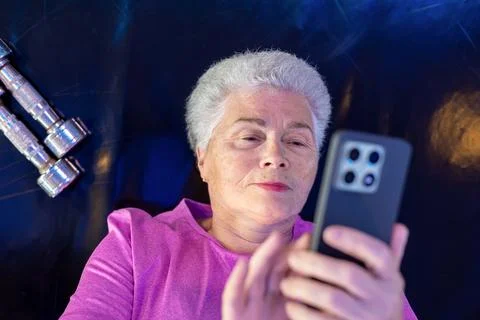 Active senior woman 75+ using smartphone while resting after workout. Stock Photos