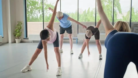 Active Seniors Doing Windmill Stretching Exercises in Gym Stock Footage 339872802