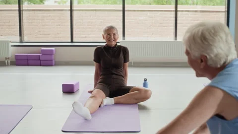 Active Seniors Talking with Instructor on Yoga Mats after Workout Stock Footage 339869276