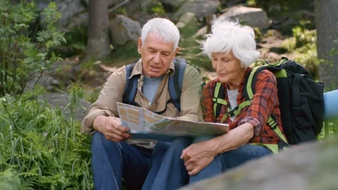 Active Seniors Using Map while Hiking in Forest Stock Footage