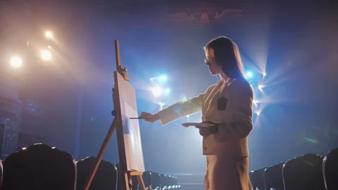 Active Side View of Female Artist Making Brush Stroke on Easel Stage Stockbeeldmateriaal 336336518