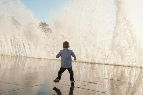 Active small kid escaping from huge water wave in city during storm weather 스톡 사진