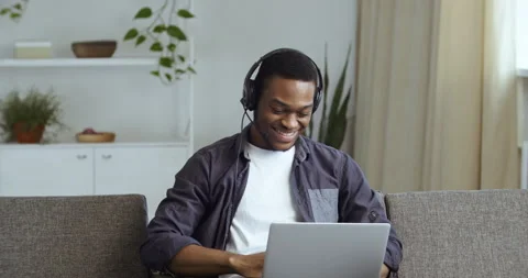 Active smiling guy afro american student man in plaid shirt sitting in interior Stock Footage 145890086