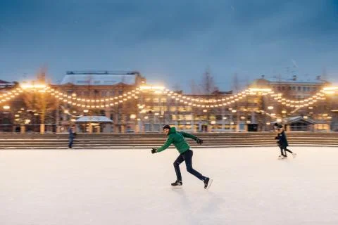 Active sorty male has fun in outdoor park on ice rink decorated with garlands Foto stock