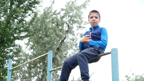Active sportive Boys Orphans do tricks Exercises on a Bars on a Yard Stock Footage 107817617