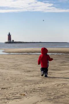An active toddler is running alone on the Lewes Beach of Delaware on a sunny day Stock Photos