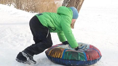 Active toddler school boy sliding down the hill on snow tube. Happy childre.. Stock Photos