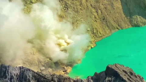 Active volcano erupting gas emission amidst a lush sulfur acid crater lake in Stock Footage 275433679