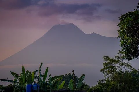 The active volcano Merapi billows smoke over the lush green landscape Foto stock