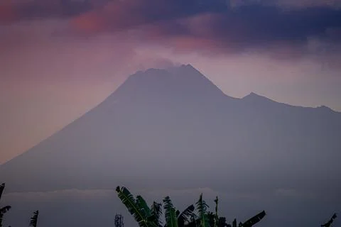 The active volcano Merapi billows smoke over the lush green landscape Foto stock