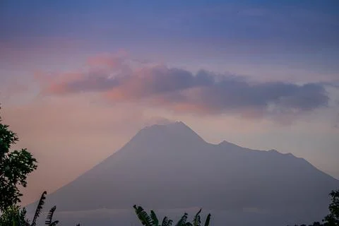 The active volcano Merapi billows smoke over the lush green landscape Stock Photos