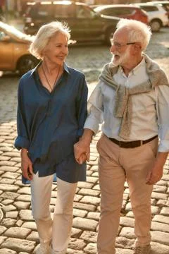 Active weekend. Elderly couple holding hands and looking to each other with Foto stock