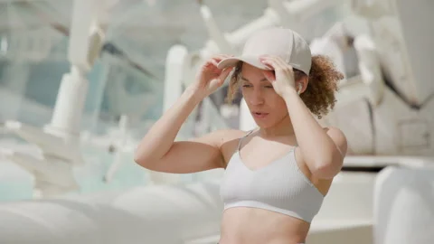 Active Woman Adjusting Cap Preparing for Workout in Modern Urban Area Stock Footage 273762818