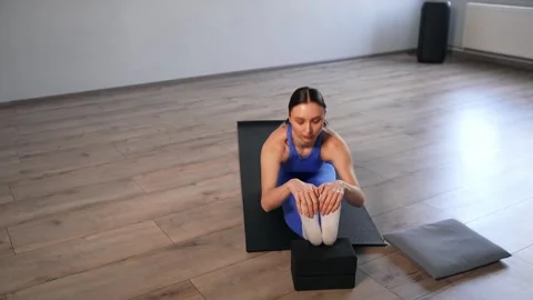 Active woman doing front splits paired with seated forward bend with yoga blocks Video stock 336490307