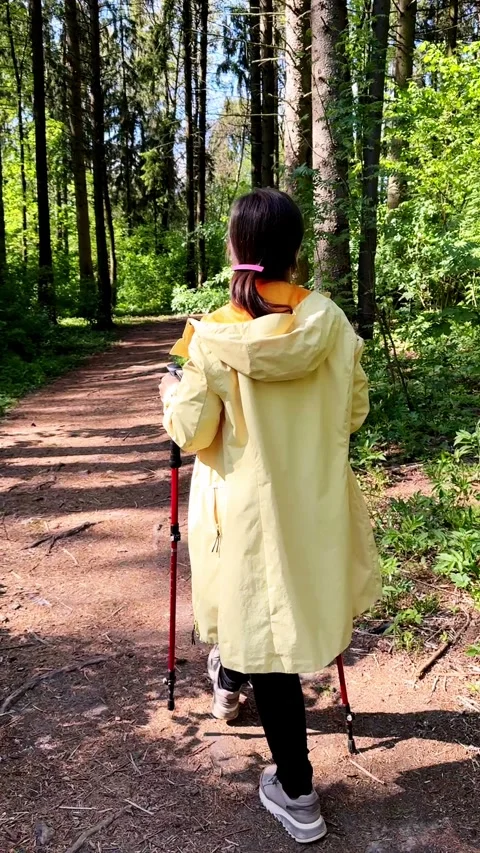 Active woman doing Nordic walking with poles in a sunny forest, combining car Video stock 310369747
