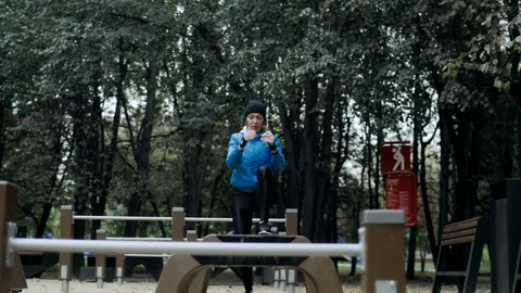 Active woman doing physical exercises in workout area. Stepping on a bench in Stock Footage 131459832