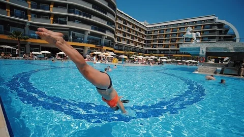 Active woman jumps into the pool refreshing water and splashes fly away Stock Footage 111079848