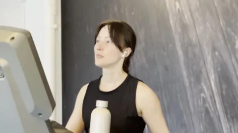 Active woman walking on treadmill while holding water bottle Stock-Footage 336272006