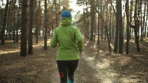 Active women's trail running in forest in the sunny day. Stock Footage
