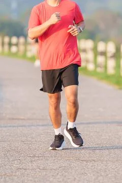Active young Asian man jogging and running in the public park at morning. M.. Stock Photos