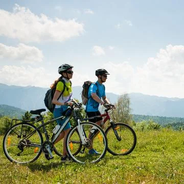 ACTIVE Young couple biking on a forest road in mountain on a spring day Stock-Fotos