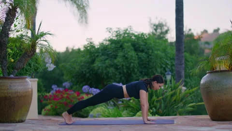 Active young girl in down- and upward-facing dog pose, training outside in a Stock Footage 210230898