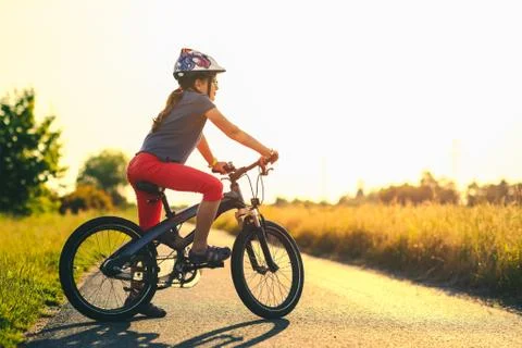 Active young girl on a mountain bicycle at sunset Stock Photos