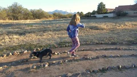 An active young girl walking her dog on a labyrinth Stock Footage 100693432