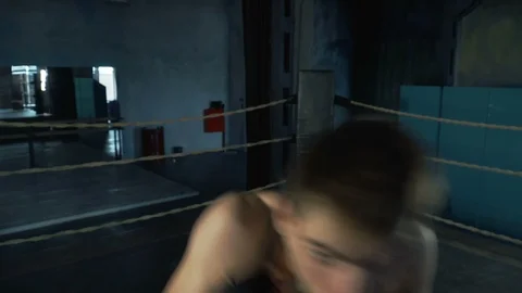 Active young man rapidly punch the camera on the boxing ring in industrial gym Stock Footage 91586942