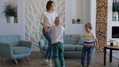 Active young mom and cute boys dancing in modern house living room, happy family Stock Footage 116656252