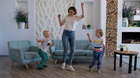Active young mom and cute boys dancing in modern house living room, happy family Vídeos de archivo 116656354