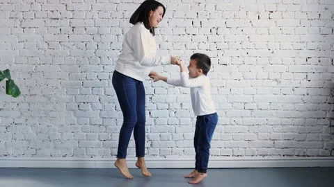 Active young mom babysiter and cute little kid son jumping dancing in modern Stock-Footage 177379766