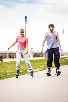 Active young people friends rollerskating outdoor. Stock Photos