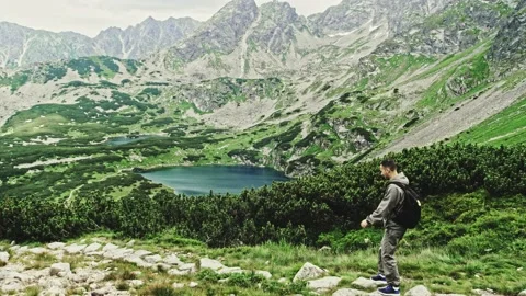Active young two tourists, a man and a woman descend from a picturesque mountain Stock Footage 165243752