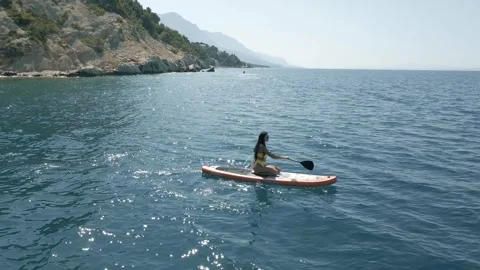 Active young woman doing exercises on water. Floating on sup board. Concept of Stock Footage 246379046