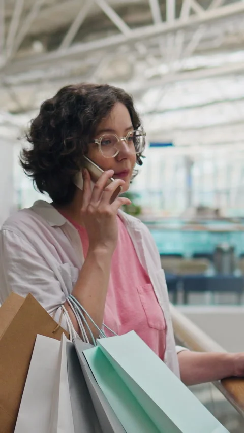 Active young woman talks on her phone while browsing summer clothing in stor Stock Footage 338199970