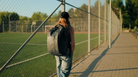 Active youth carrying heavy backpack along outdoor sports court. Stock Footage 339808647