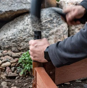 Actively driving a border stake with a rubber mallet to assemble a raised bed Stock Photos